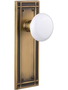 an antique brass door handle with a white glass ball on the front and side panel