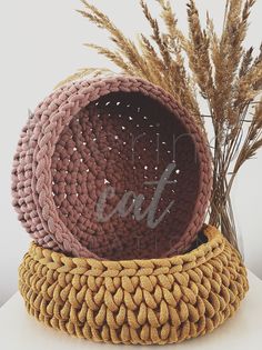 a woven basket sitting on top of a table next to some dried grass and a vase