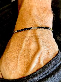 a man wearing a black beaded bracelet