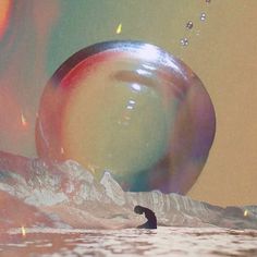 a person is standing in the water with bubbles floating around him and there are mountains in the background