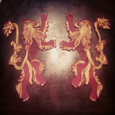 two red and yellow lions on a black surface with gold trimmings in the middle