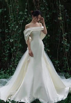 a woman in a white wedding dress is posing for the camera with her hand on her face