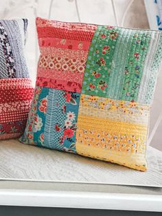 two colorful pillows sitting on top of a white chair