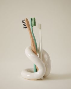 three toothbrushes are in a white holder