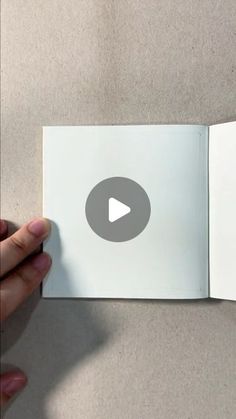 someone is holding an open book with a video on the page and pointing at it