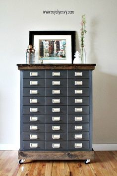 an old filing cabinet with lots of drawers on it and a framed picture above the top