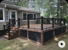 a wooden deck with black iron railings in front of a house