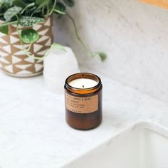 a candle sitting on top of a counter next to a potted plant in a bathroom