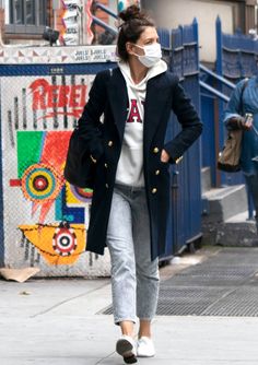 a woman walking down the street wearing a face mask