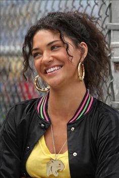 a smiling woman in a yellow shirt and black jacket