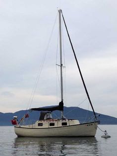 a small sailboat in the water with mountains in the background