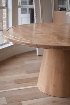 a round wooden table in front of a window