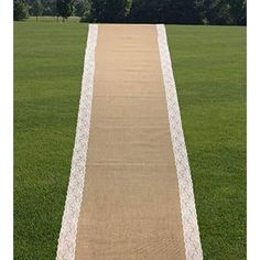 a long white and beige runner in the middle of a field with trees in the background