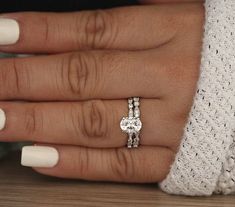 a woman's hand with two engagement rings on her fingers and the other hand holding an engagement ring