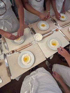 several people in white aprons are preparing food on plates and serving utensils