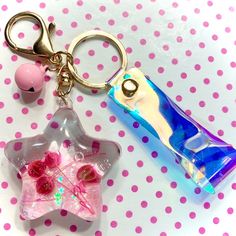 two key chains that are on top of a pink and white polka dot tablecloth