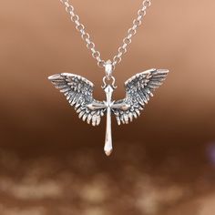 a silver cross with wings on a chain