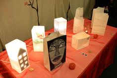 some paper bags sitting on top of a table with lights and decorations around them that look like faces