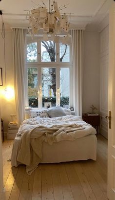 a bedroom with a large bed and a chandelier hanging from it's ceiling