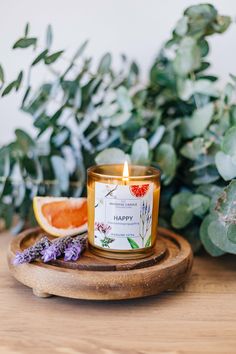 a candle sitting on top of a wooden plate next to a grapefruit and orange slice