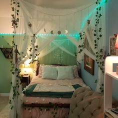 a bedroom decorated in green and white with lots of greenery on the bed canopy