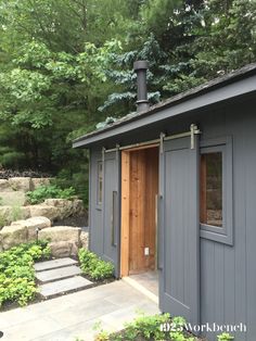 a small gray shed sitting in the middle of a forest