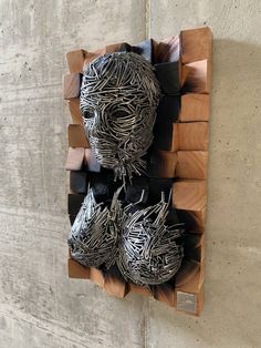 a sculpture made out of metal wire and wood on the side of a concrete wall