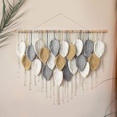 the wall hanging is decorated with different colors and sizes of leaves, which are hung on a wooden stick