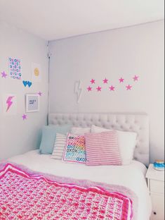 a white bed topped with pillows and pink blankets