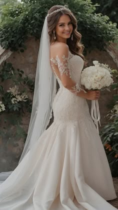 a woman in a wedding dress holding a bouquet and posing for the camera with her veil over her head