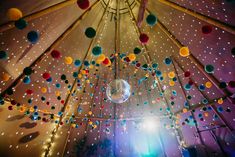 a disco ball hanging from the ceiling in a tent with lights and decorations on it