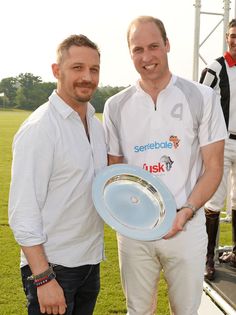 two men standing next to each other on a soccer field holding a blue and white plate