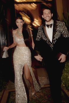 a man in a tuxedo standing next to a woman wearing a sequin dress