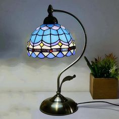 a lamp that is sitting on top of a table next to a potted plant