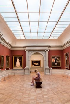 a person sitting on a bench in an art gallery