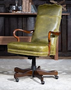 a green leather office chair sitting in front of a wooden shelf with books on it