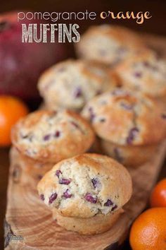 some muffins are sitting on a cutting board next to oranges