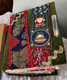 an open book covered in christmas fabric on top of a white table cloth next to a ruler