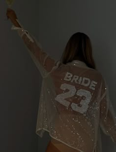 a woman is standing in the dark with her arms spread out and wearing a white shirt that says bride twenty