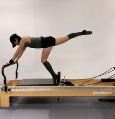 a woman is doing an exercise on a rowing machine while wearing black tights and knee pads