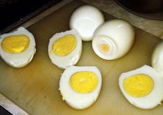 four hard boiled eggs sitting on top of a cutting board next to an egg shell