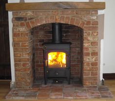 a brick fireplace with a wood burning stove in the center and an open door to another room