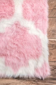 a pink and white fur pillow on top of a wooden floor