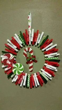 an ornament made out of candy canes is hanging on the wall in front of a christmas wreath