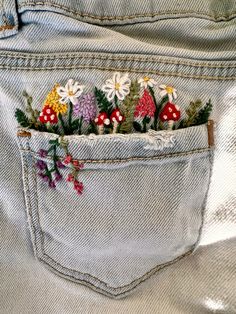 the back pocket of a pair of jeans with embroidered flowers and mushrooms on them,