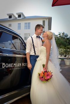 a bride and groom standing in front of a black car with the word bohemian hotel written on it