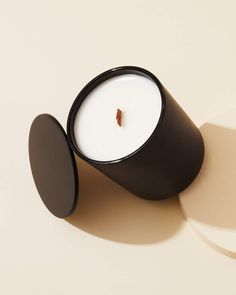 a small black candle sitting on top of a white table next to a round object