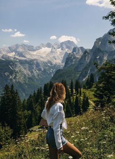 a woman standing on top of a lush green hillside