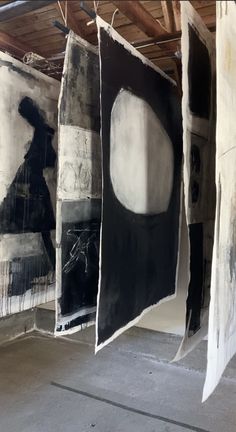 three black and white paintings hanging from the ceiling