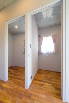 an empty room with wooden floors and two doors leading to another room in the background